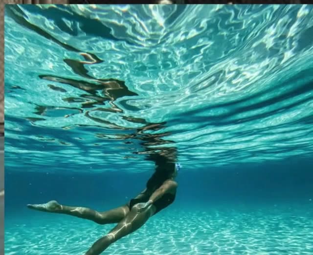 A swimmer underwater in turquoise light